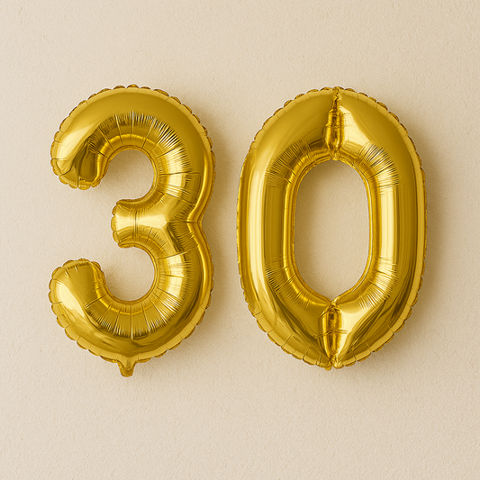 Gold number balloons spelling '30' on a beige background