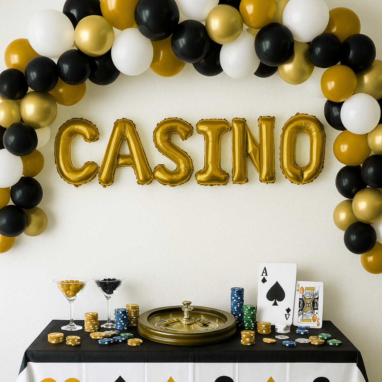 Decorated table with 'CASINO' balloons and casino-themed items against a white wall.