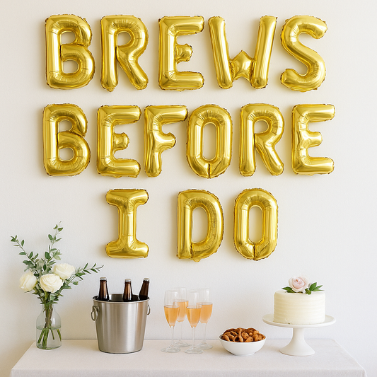 Gold balloon letters spelling 'BREWS BEFORE I DO' above a table with drinks and a cake.
