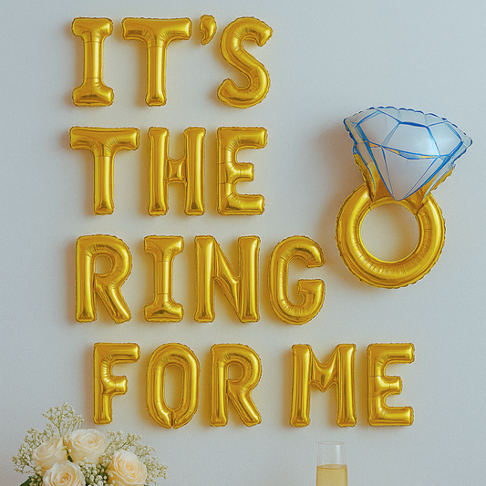 Gold balloon letters spelling 'IT'S THE RING FOR ME' with a diamond ring balloon on a light gray background.