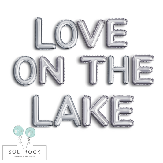 Silver balloon letters spelling 'LOVE ON THE LAKE' with Sol + Rock logo below.