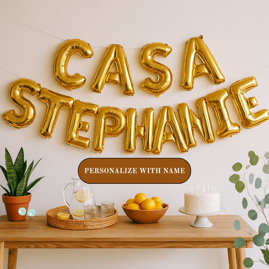 Gold balloon letters spelling 'CASA STEPHANIE' above a table with decor items.