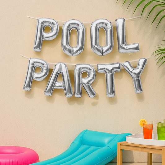 Silver 'POOL PARTY' balloons against a beige wall with a poolside setup.