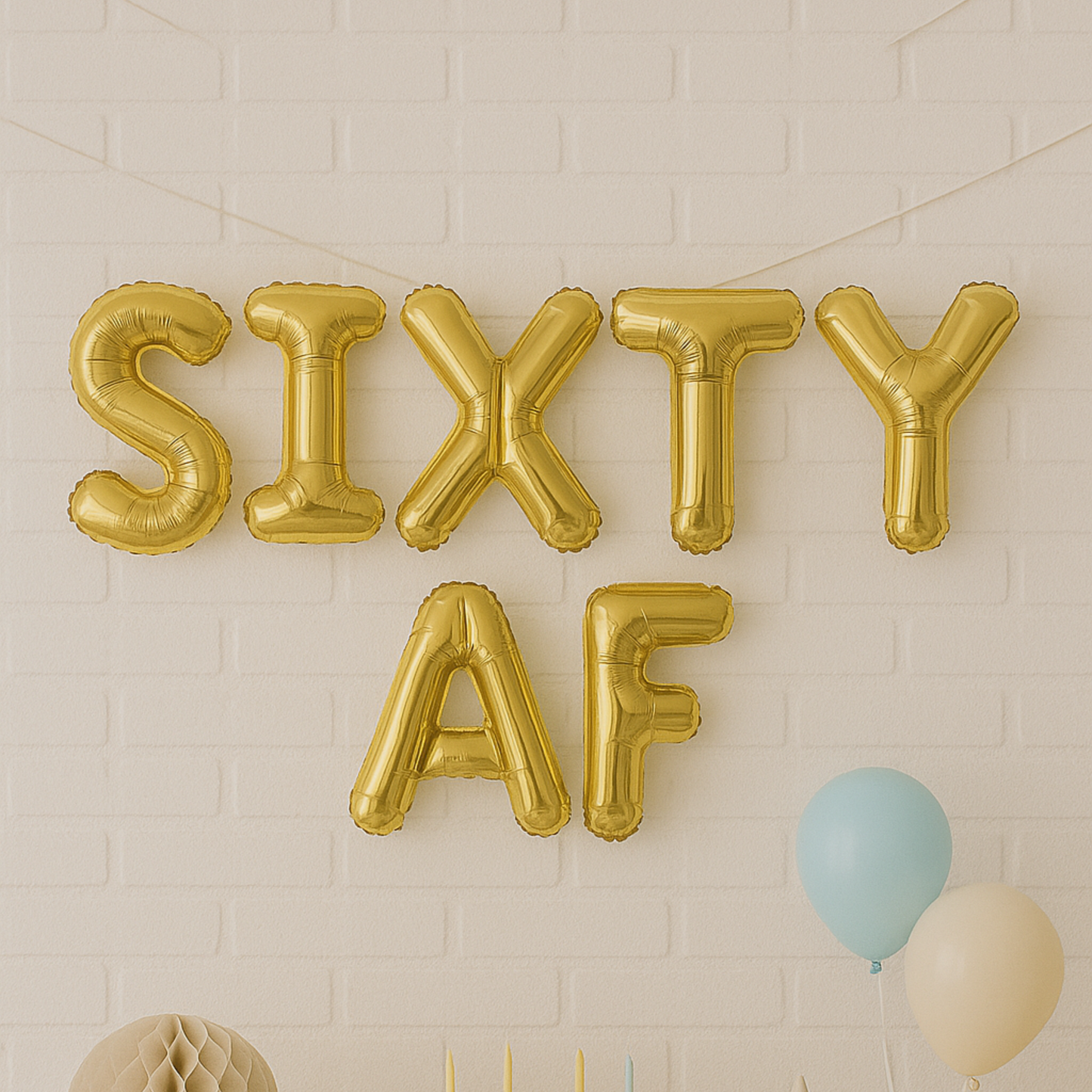 Gold 'SIXTY AF' balloons against a light brick wall.