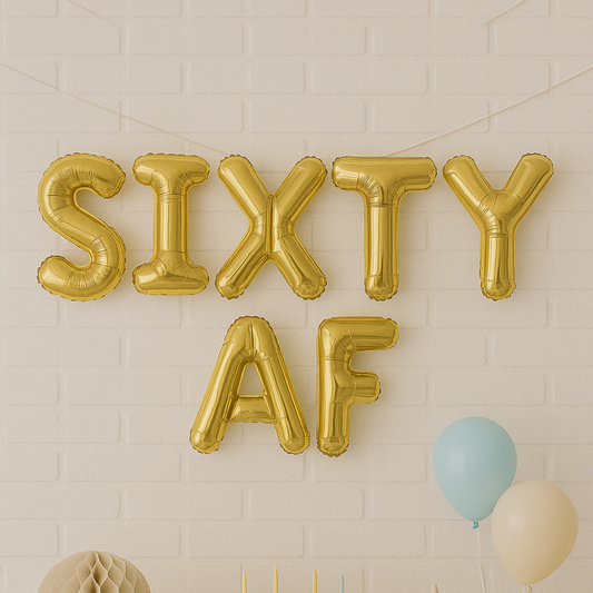 Gold 'SIXTY AF' balloons against a light brick wall.