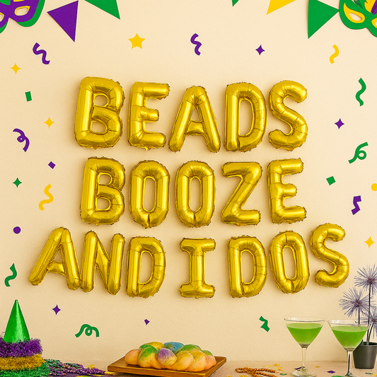 Gold foil balloon banner spelling “Beads Booze and I Dos” above a Mardi Gras-themed party table
