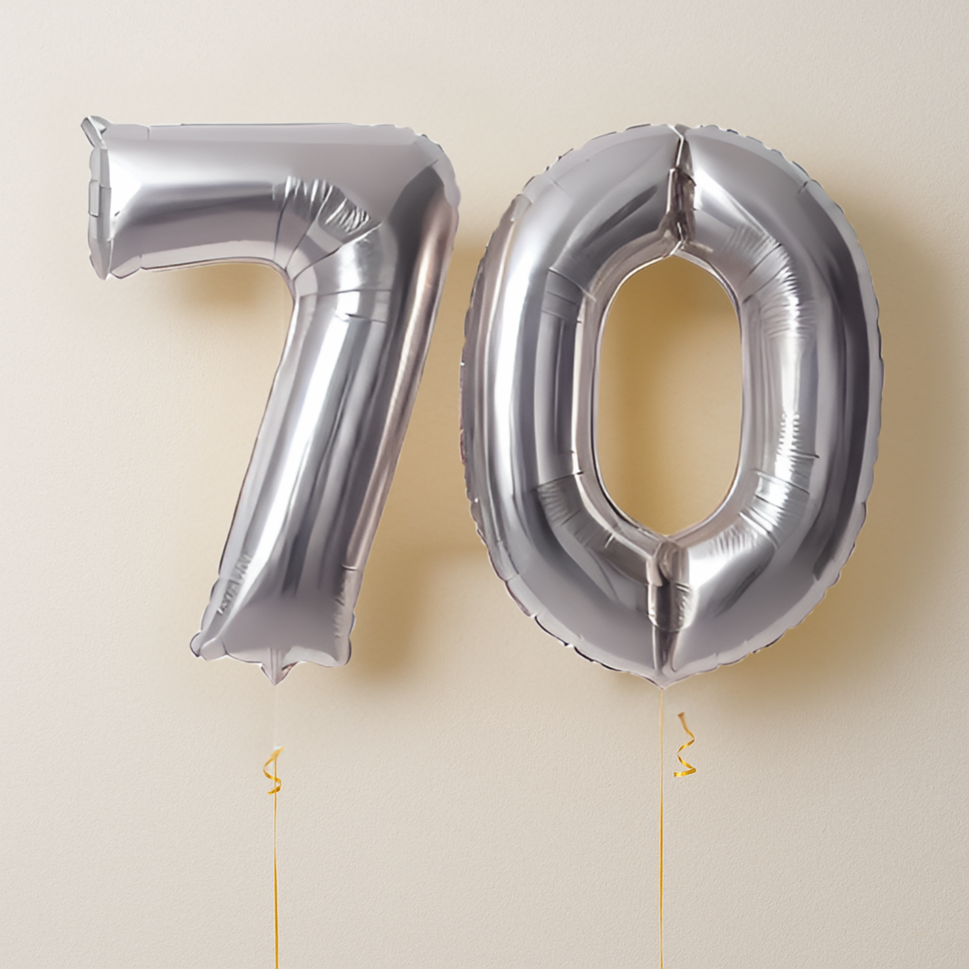 Silver number '70' balloons on a beige background