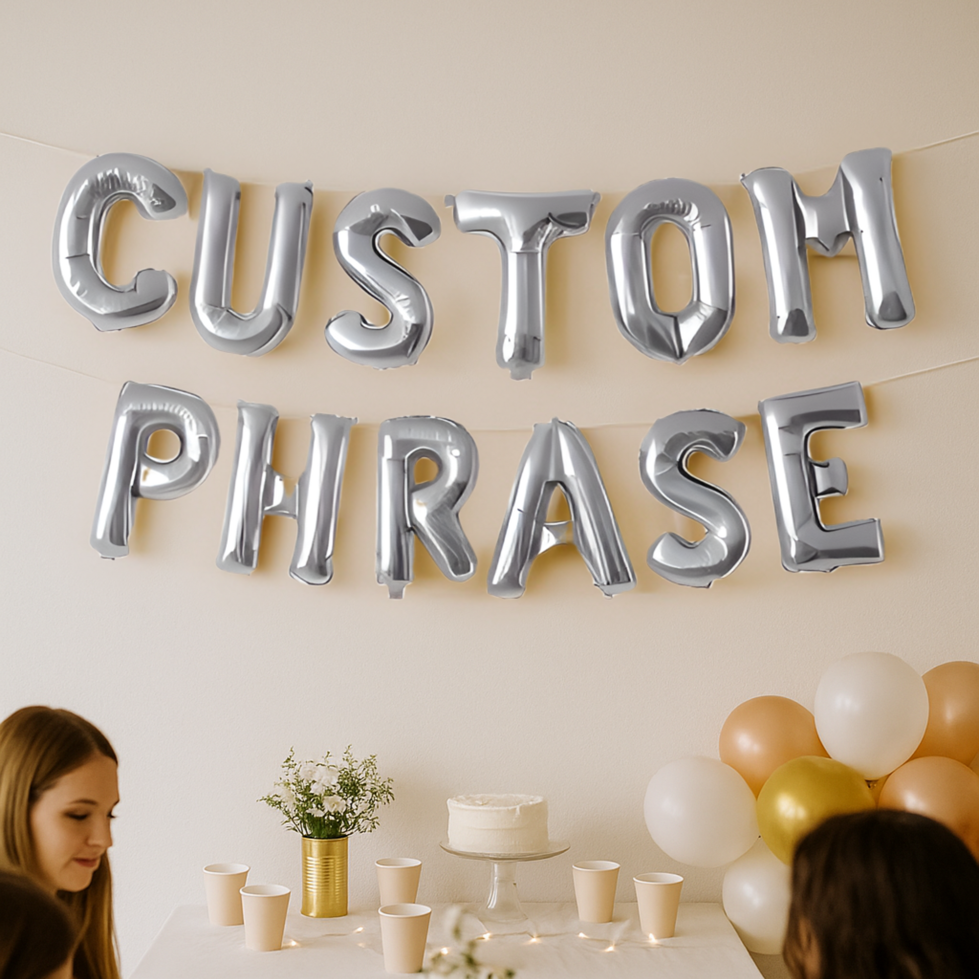 Silver letter balloons spelling 'CUSTOM PHRASE' with a table setup in the background.