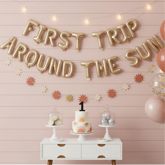 Decorated room with 'First Trip Around the Sun' banner, balloons, and a cake on a checkered floor.