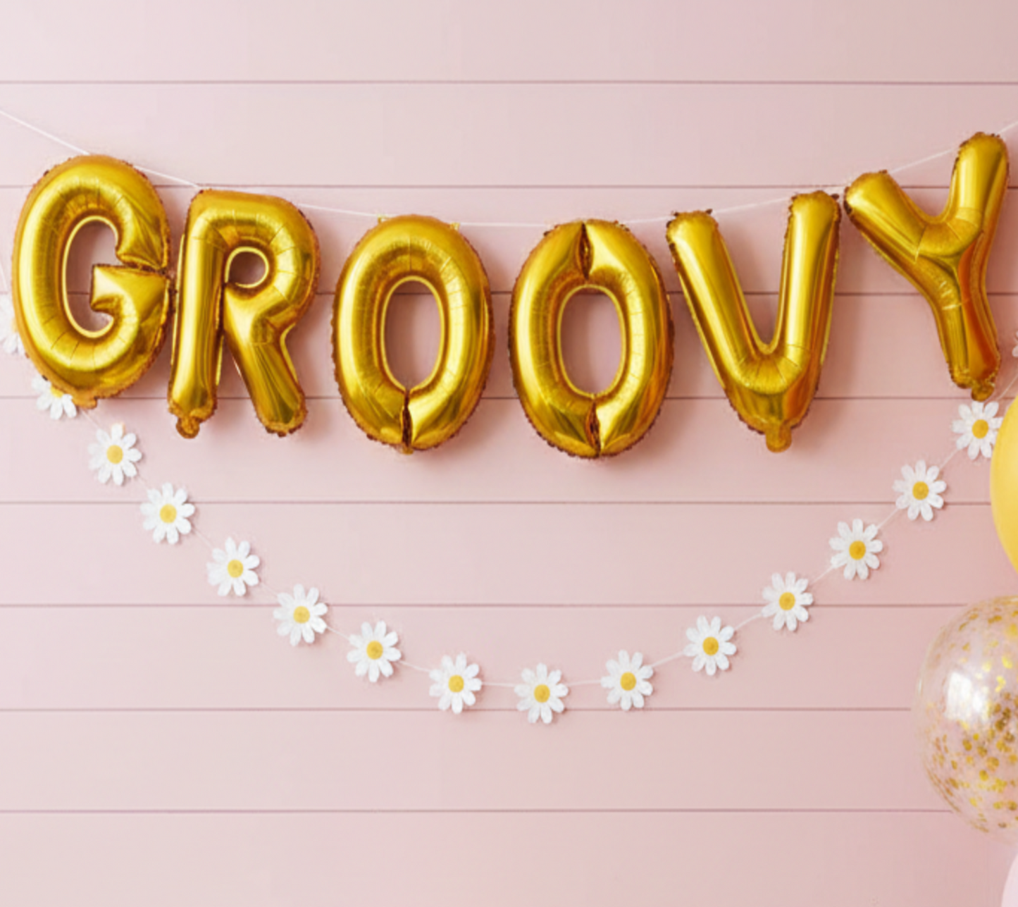 Decorated room with 'Groovy' balloons, balloons on a stand, and a cake on a table.