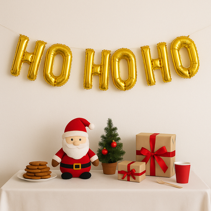 Christmas-themed setup with gold 'HO HO HO' balloons, Santa figurine, cookies, small tree, and presents on a table.