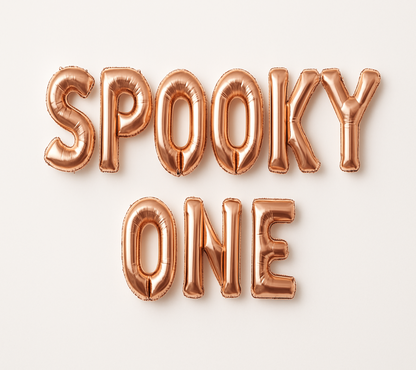 SPOOKY ONE in rose gold foil letter balloons on white background.
