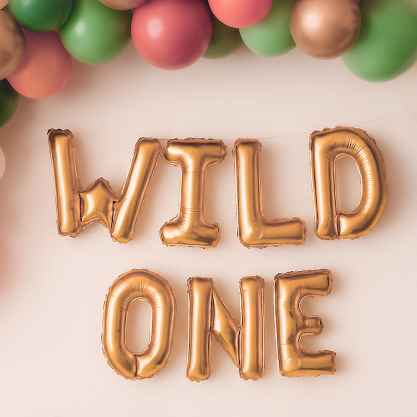 Gold 'WILD ONE' balloons with colorful balloons in the background