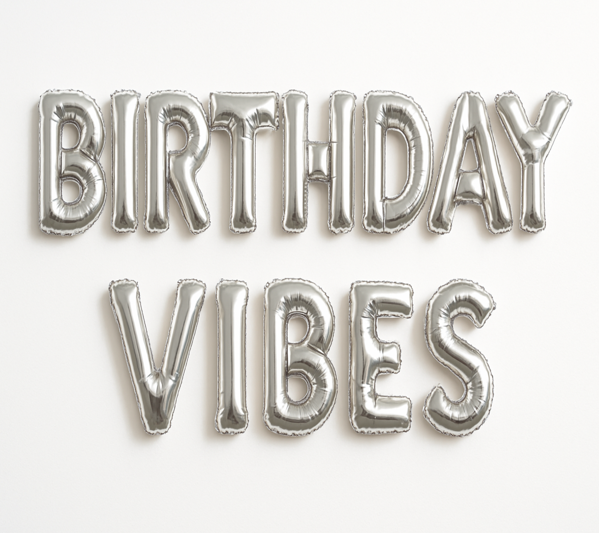 BIRTHDAY VIBES in silver foil letter balloons on white background.
