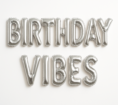 BIRTHDAY VIBES in silver foil letter balloons on white background.
